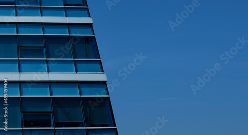 business building in city with mirror windows with reflections of blue sky.