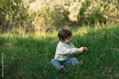 Cheerful happy child is playing on the green meadow. Smiling little boy on nature.