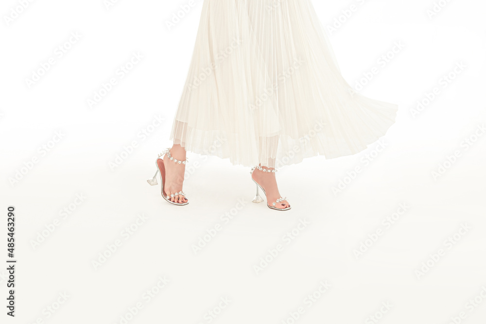 Young woman in elegant dress, white shoes standing isolated on white background Young woman in elegant dress, white shoes standing isolated on white background