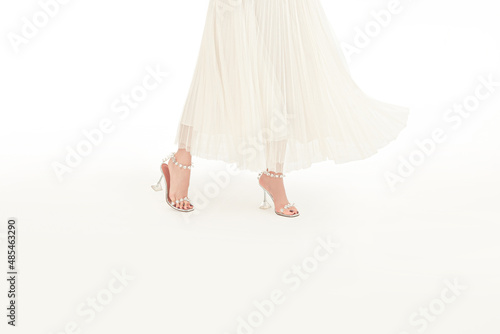 Young woman in elegant dress, white shoes standing isolated on white background