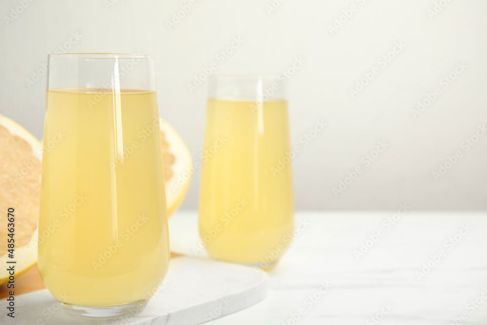 Glasses of fresh pomelo juice on white table. Space for text Glasses of fresh pomelo juice on white table. Space for text