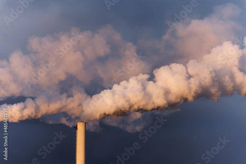 rauchender Schornstein im Abendlicht vor blauem Himmel