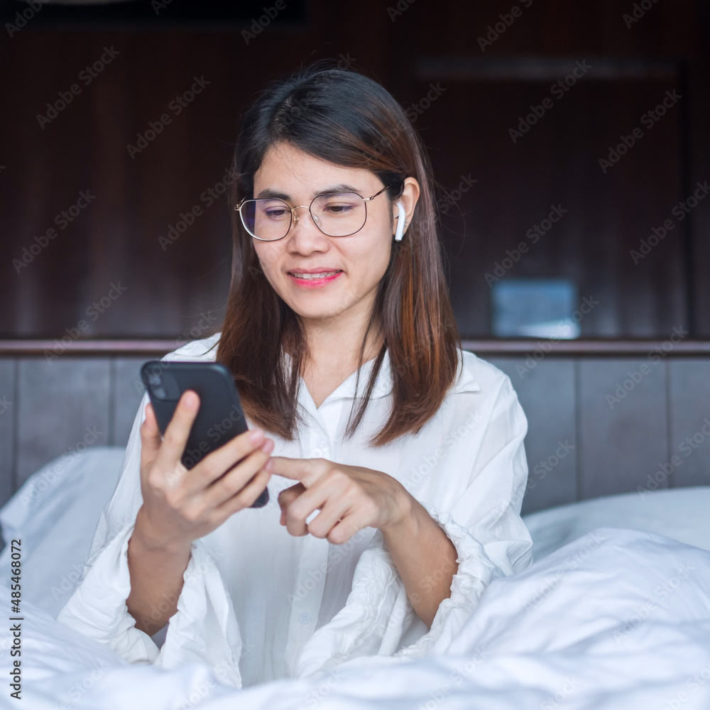 Happy woman using smart phone for video call, female meeting  online by mobile phone on bed. technology, network, work from home, lifestyle and digital communication concept