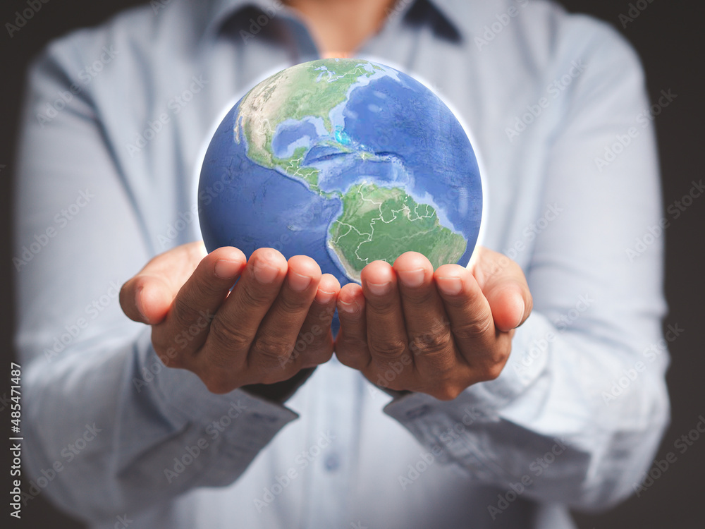 Young man holding the earth while standing against a gray background. Young man holding the earth while standing against a gray background.