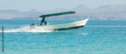 A man on a boat or panga at high speed on the sea of cortes near Isla Espiritu Santo in the baja peninsula, Baja California Sur. Mexico photo
