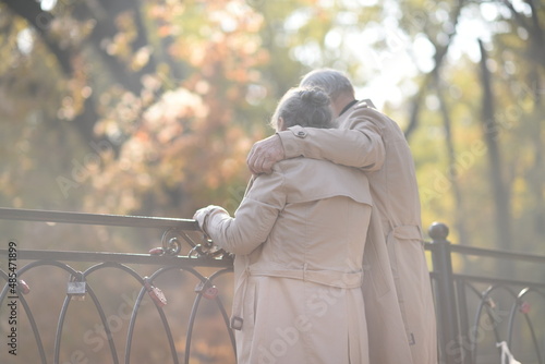 Old happy loving couple holding hands hugs looks