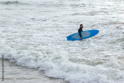Photography Man with beard and curly hair standing in waves