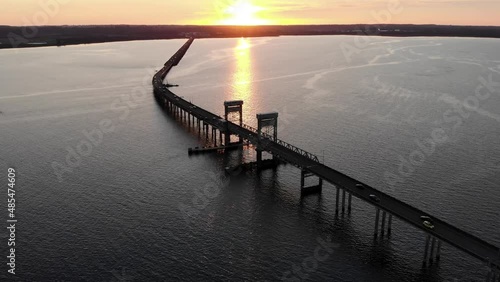 Cinematic aerial sunset view of New Youngs Bay bridge connecting Washington and Oregon United States. Drone fly above the bridge driving cars over the ocean during epic golden hours photo