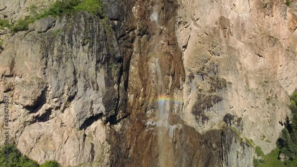 alpine waterfall from the rocky wall with rainbow colors, aerial bottom to top shot alpine waterfall from the rocky wall with rainbow colors, aerial bottom to top shot
