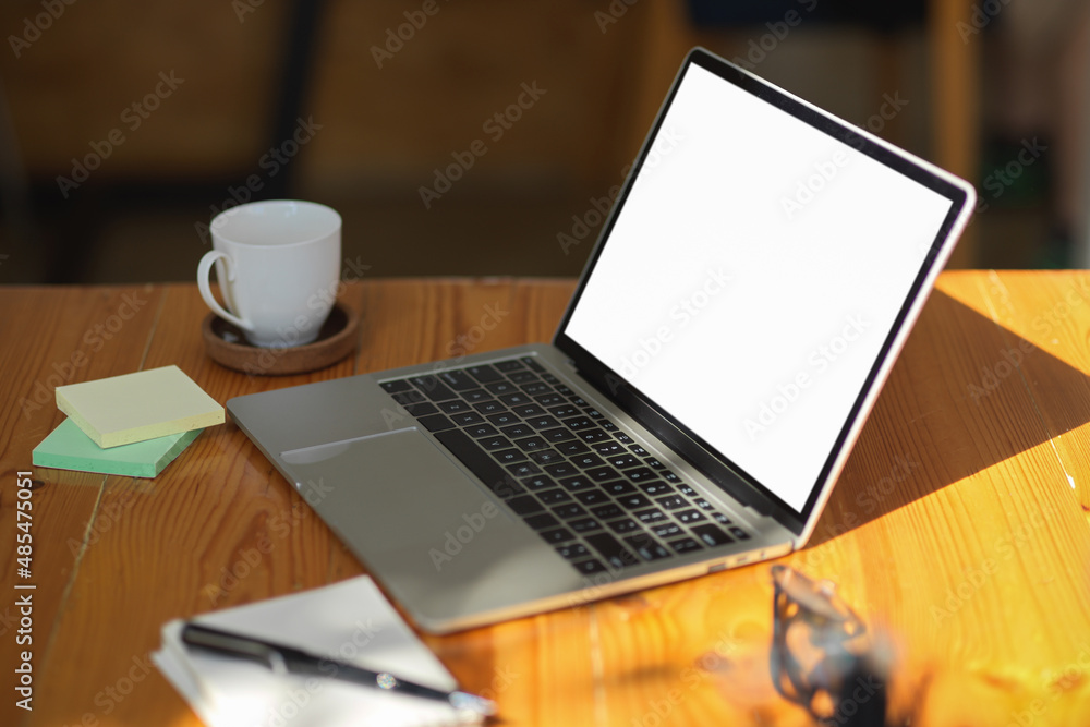 Fototapeta premium Notebook laptop computer white screen mockup on wooden table.