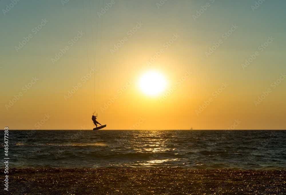 Kite boarder performing a jump at sunset