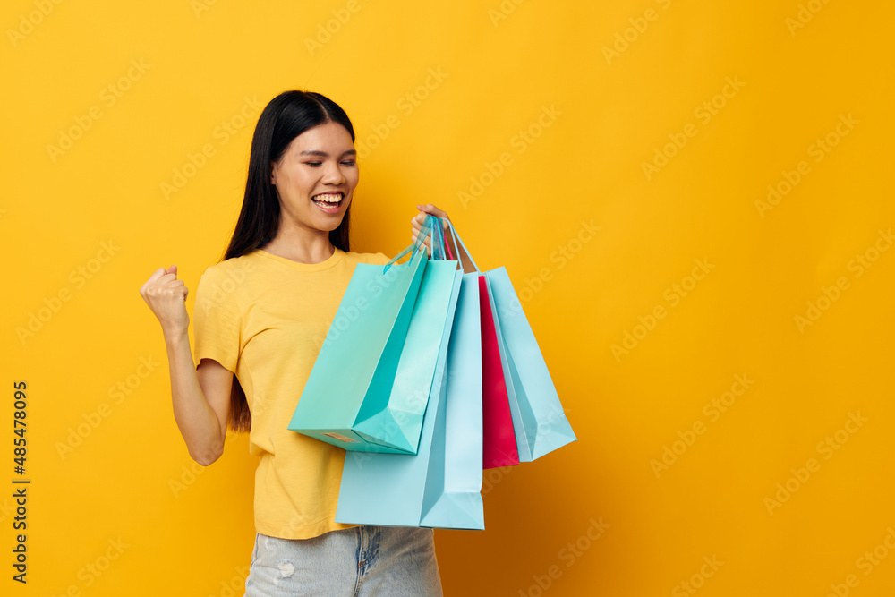 Charming young Asian woman with packages in hands shopping isolated background unaltered