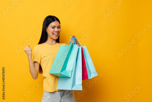 Charming young Asian woman with packages in hands shopping isolated background unaltered