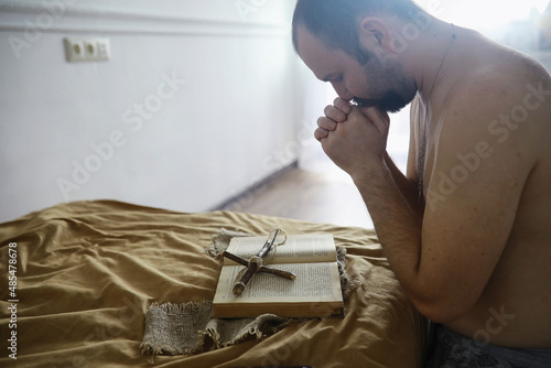 Man reading and pray from the holy bible near the bed in the evening. Christians and Bible study concept. Studying the Word Of God in church.