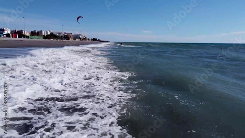 Kite surfer in the ocean outside Nerja Spain. Popular sport on the Spanish coast. High waves crashing in at the Playa Playazo beach in Nerja. High rise buildings in the background. photo