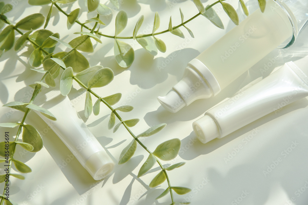 Cosmetic bottle containers packaging with green herbal leaves in shadow and light effect, Blank label for organic branding mock-up, Natural skincare beauty product concept.
