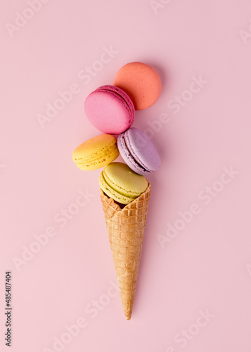 Colorful delicious macaron or macaroons in an ice cream waffle cone. Summer dessert