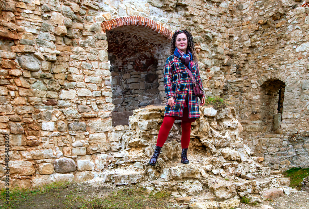 Pretty woman with curly hair stands on the ruins of an medieval castle remains in Koknese, Latvia. Built shortly after 1209. Pretty woman with curly hair stands on the ruins of an medieval castle remains in Koknese, Latvia. Built shortly after 1209.