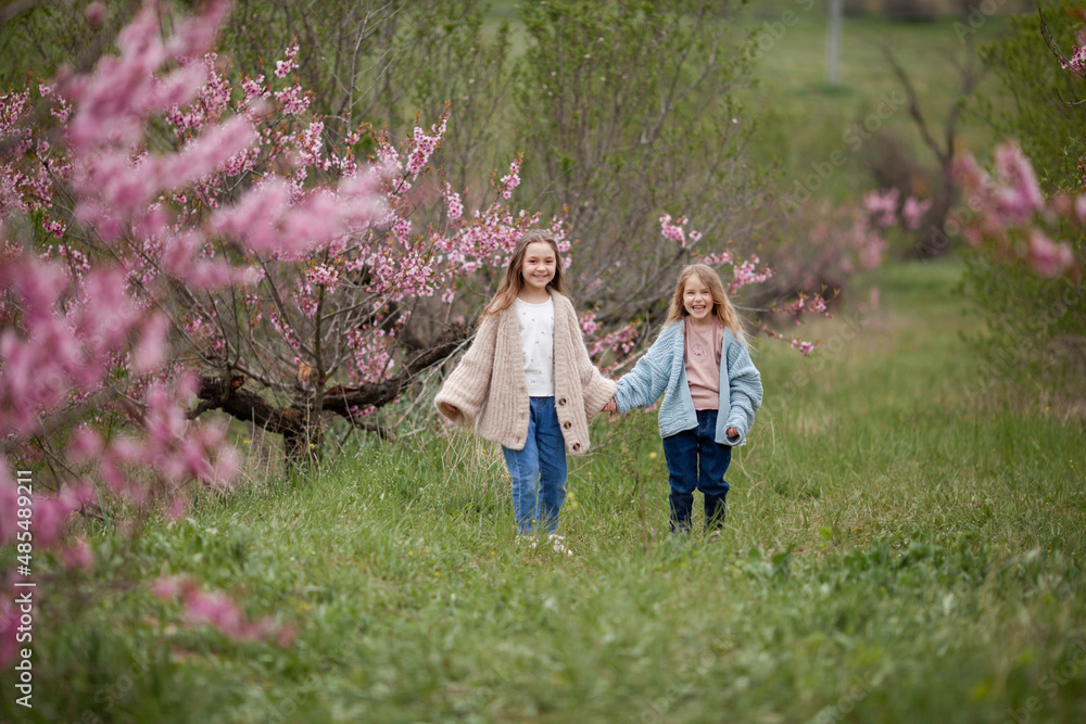 Fototapeta premium Pretty girls 7-10 year old with flowers over blooming nature background close up. Spring season. Childhood.