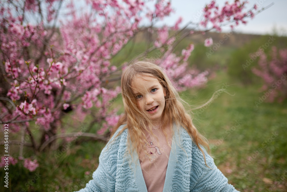 Pretty little child girl 6-7 year old with flowers over blooming nature background close up. Spring season. Childhood. Pretty little child girl 6-7 year old with flowers over blooming nature background close up. Spring season. Childhood.