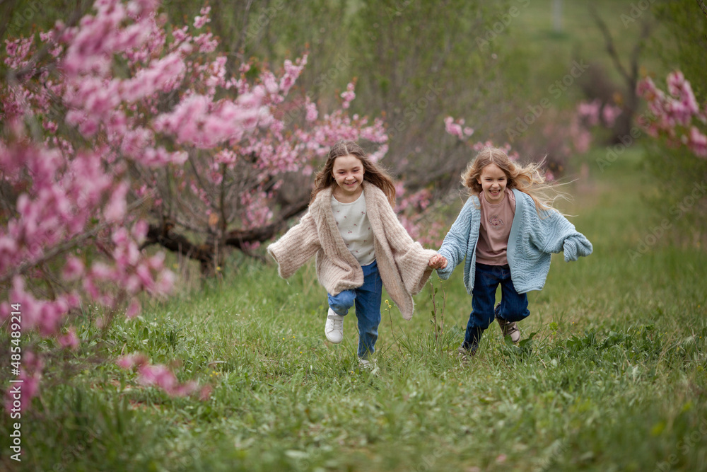 Obraz premium Pretty girls 7-10 year old with flowers over blooming nature background close up. Spring season. Childhood.