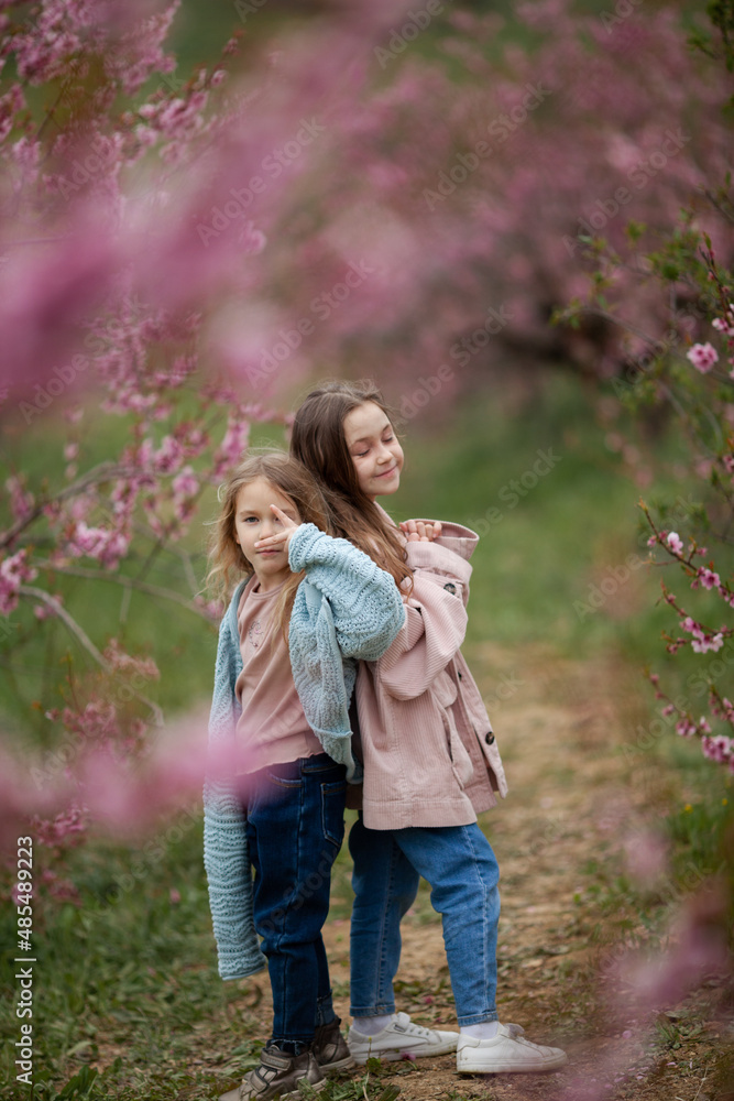 Fototapeta premium Pretty girls 7-10 year old with flowers over blooming nature background close up. Spring season. Childhood.