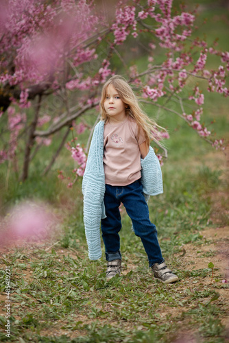 Pretty little child girl 6-7 year old with flowers over blooming nature background close up. Spring season. Childhood.