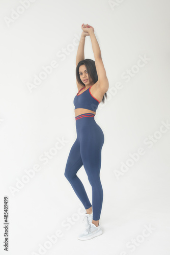 Full length of strong attractive african american sportswoman in sports bra and leggings standing over white background. 