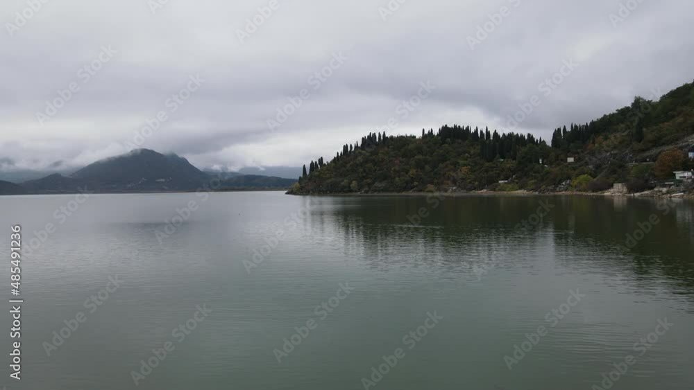 Drone shot of storm clouds over a distant, dark, lonely island beside the pristine lake in Montenegro. Drone shot of storm clouds over a distant, dark, lonely island beside the pristine lake in Montenegro.