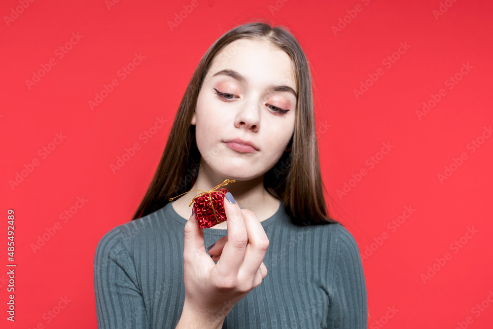Expectation is reality. Birthday. Christmas. A small gift for the new year. A cute girl is holding a small red box in her hands Expectation is reality. Birthday. Christmas. A small gift for the new year. A cute girl is holding a small red box in her hands