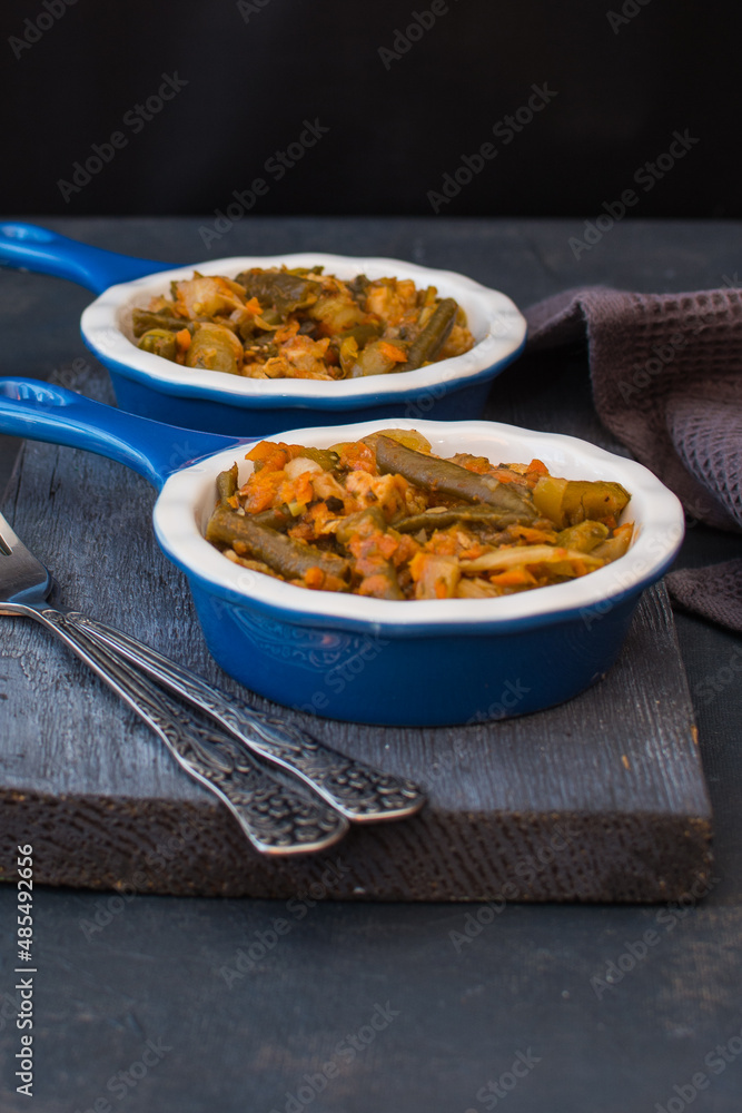 Vegetable stew with green beans and cauliflower and sweet peppers in a ceramic bowl on a wooden stand.
Vegetable stew with green beans and cauliflower and sweet peppers in a ceramic bowl on a wooden stand.