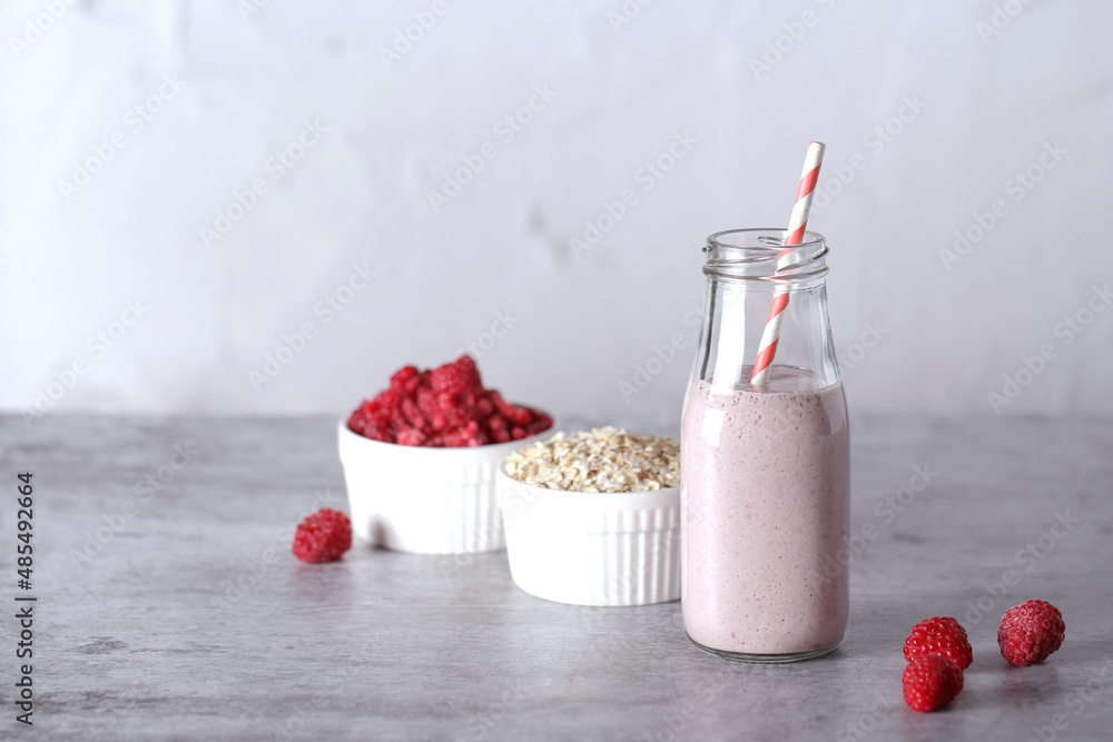 a smoothie with raspberries and oatmeal and milk stands on a gray background, there is a place to record a smoothie with raspberries and oatmeal and milk stands on a gray background, there is a place to record
