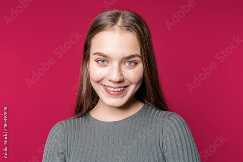 Smiling woman. Student. Portrait of a beautiful girl in casual clothes on a red background