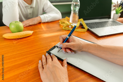 Fighting childhood obesity. Kid bored by what doctor says. Doctor talking with child and writing diet plan. Childhood obesity problem. Doctor examining boy in clinic. Boy at a nutritionist appointment