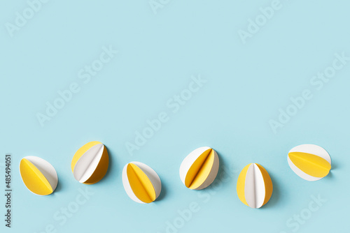 Yellow paper crafting eggs on blue background  easter and spring concept