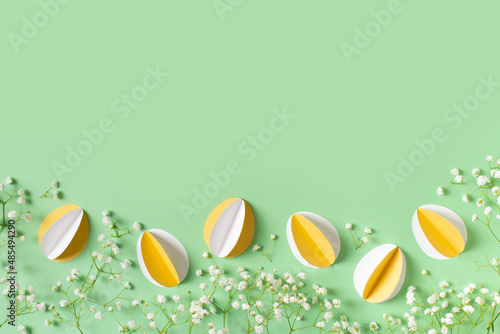 Yellow paper crafting eggs on green background, easter and spring concept photo