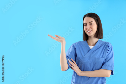 Attractive female trainee nurse on blue background