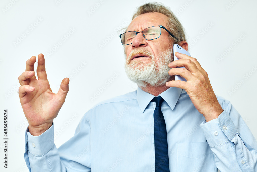 Photo of retired old man in a shirt with a tie talking on the phone isolated background Photo of retired old man in a shirt with a tie talking on the phone isolated background
