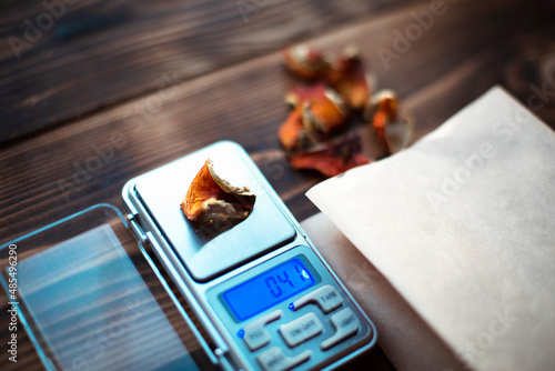 Dried pieces of mushroom fly agaric on table with scales. Measurement of microdose, microgram of psychedelic, therapeutic narcotic substance in poisonous Amanita muscaria. Microdosing, psychotropic