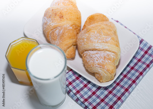 Delicious breakfast with fresh croissants, orange juice and a glass of milk.