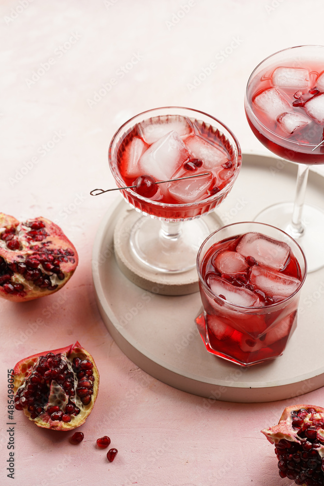 three glasses with fresh pomegranate juice with one real pomegranate on concrete tray on pink background three glasses with fresh pomegranate juice with one real pomegranate on concrete tray on pink background