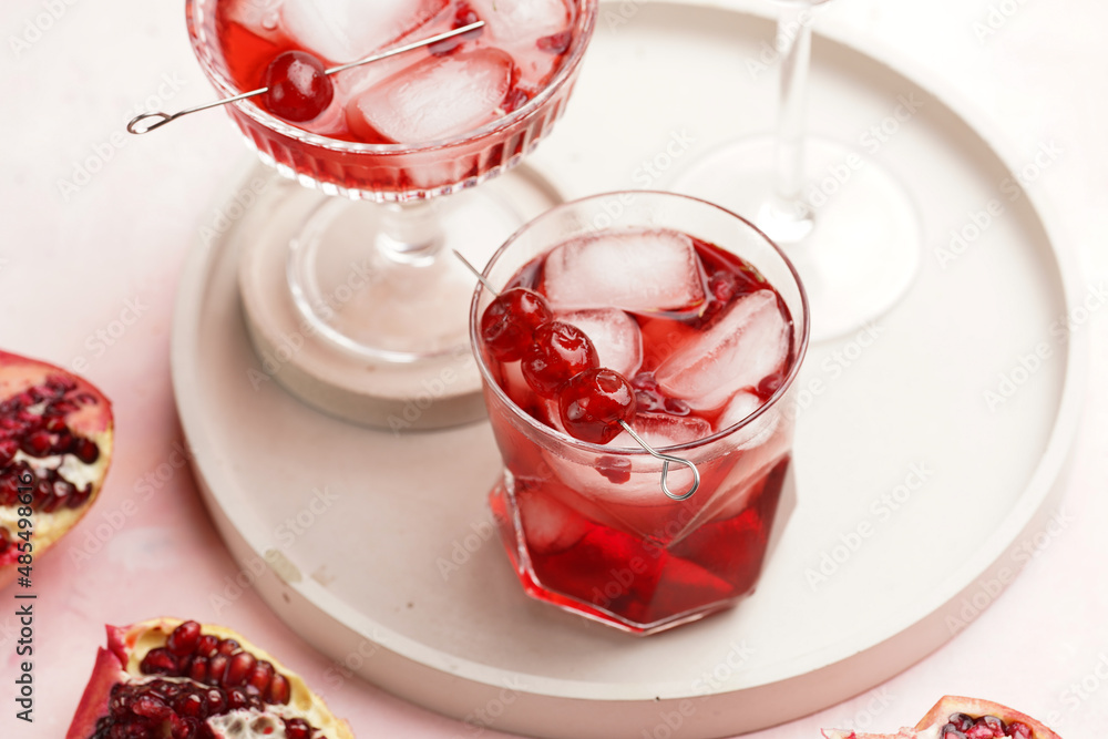 three glasses with fresh pomegranate juice with one real pomegranate on concrete tray on pink background three glasses with fresh pomegranate juice with one real pomegranate on concrete tray on pink background