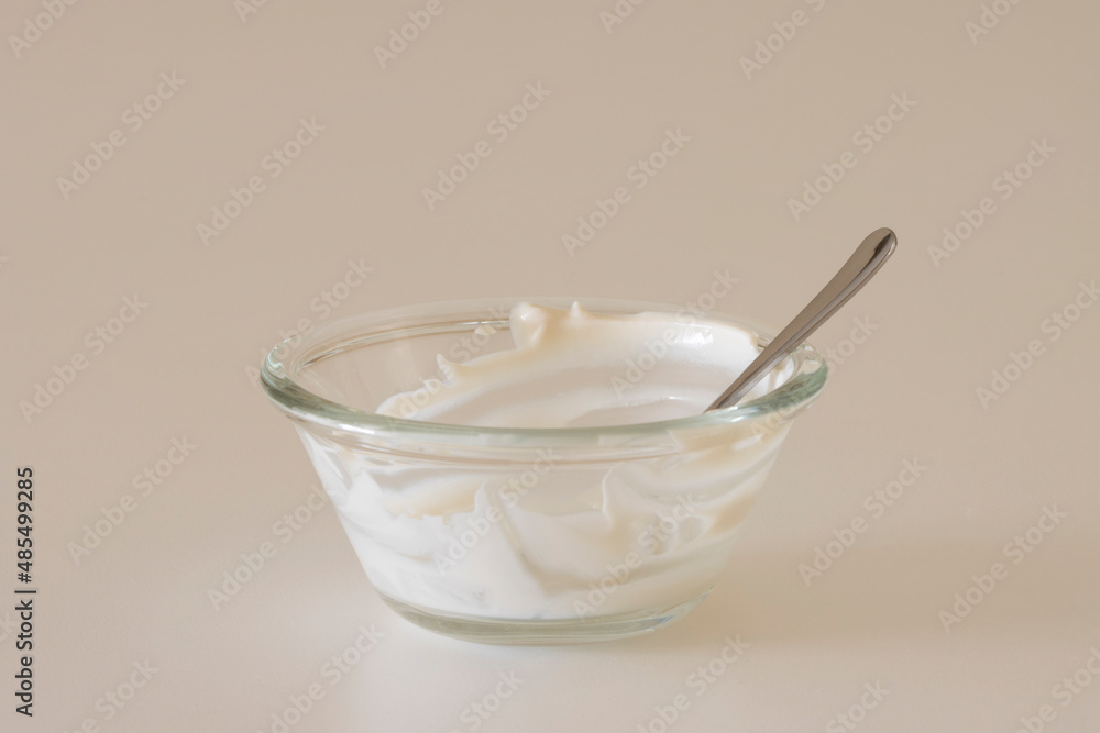 Empty yogurt bowl, with a spoon in it, isolated on a white background. Creamy plant-based yogurt, dairy-free vegan food, ketogenic diet, and healthy nutrient-packed snack concept. Empty yogurt bowl, with a spoon in it, isolated on a white background. Creamy plant-based yogurt, dairy-free vegan food, ketogenic diet, and healthy nutrient-packed snack concept.