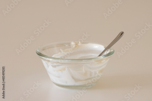 Empty yogurt bowl, with a spoon in it, isolated on a white background. Creamy plant-based yogurt, dairy-free vegan food, ketogenic diet, and healthy nutrient-packed snack concept.