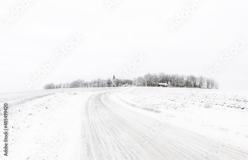 Farm barn and house in a cold winter landscape with snow and frost