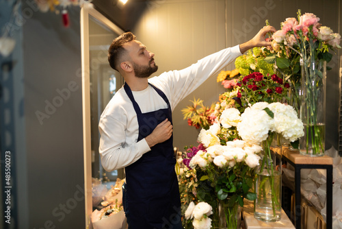 a botanist in a flower shop adjusts a display case with fresh cut flowers