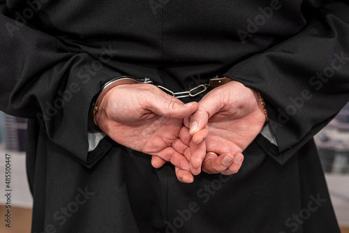 a young man nicely dressed in a dark suit is detained for counterfeit dollar bills.