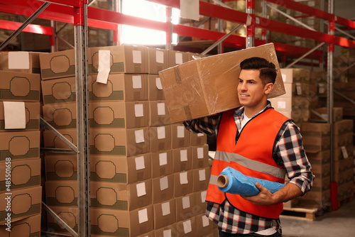 Worker with roll of stretch film and wrapped box in warehouse photo