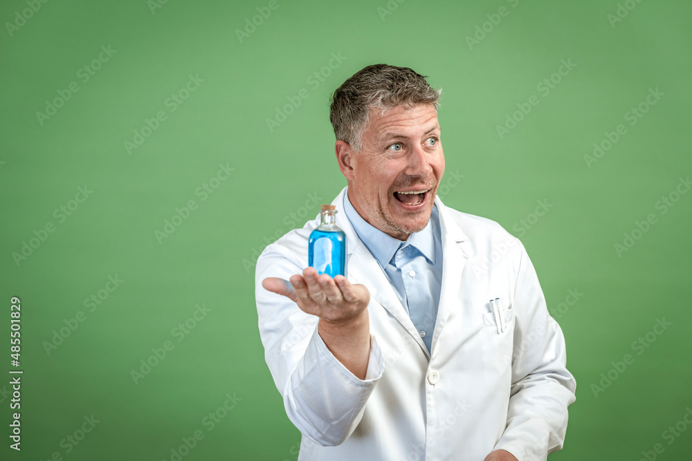 Scientist with white coat holding small flask with blue liquid and is standing in front of green background Scientist with white coat holding small flask with blue liquid and is standing in front of green background