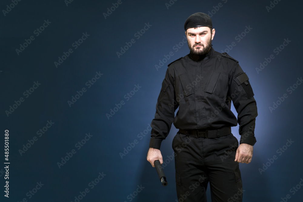 Bodyguard. A male security guard in a black uniform and a cap took a protective stance. Defender. Private security. Mercenary Bodyguard. A male security guard in a black uniform and a cap took a protective stance. Defender. Private security. Mercenary